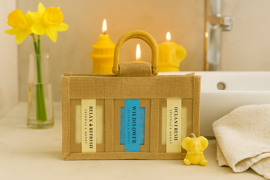 Natural jute gift bag with three handmade beeswax and honey soaps displayed in a cozy bathroom with candles and flowers for a rustic spa look