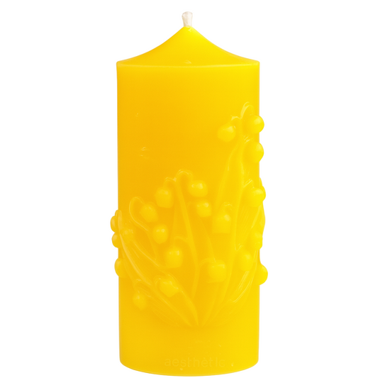 Yellow beeswax candle with embossed design on a white background